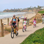 Family riding ther bikes on the boardwalk in Pacific Beach